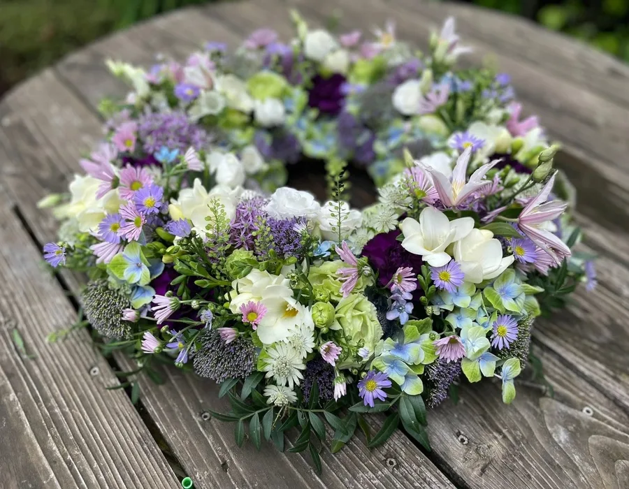 Bårekrans bundet med sæsonens blomster i lyse farver