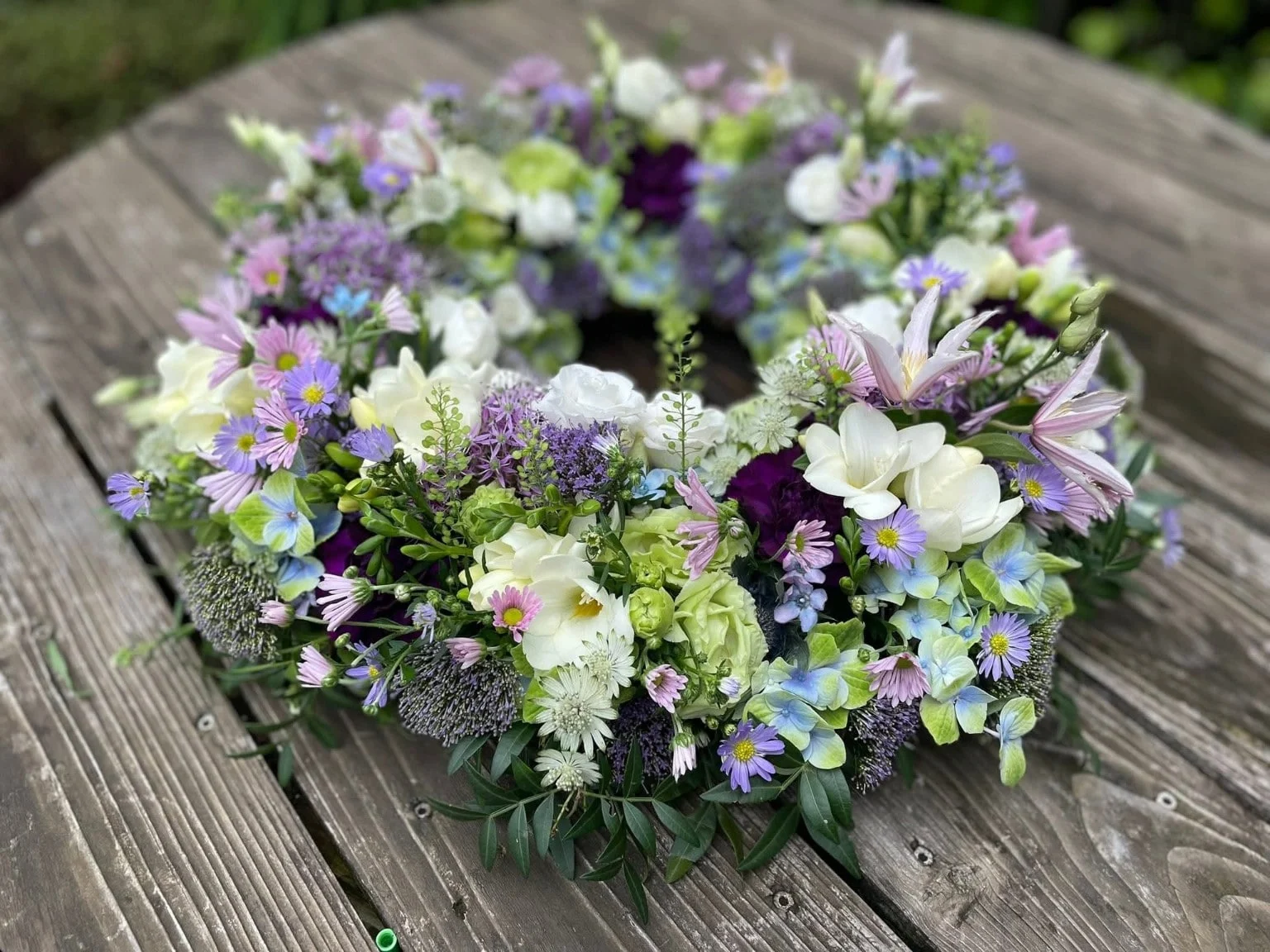 Bårekrans bundet med sæsonens blomster i lyse farver