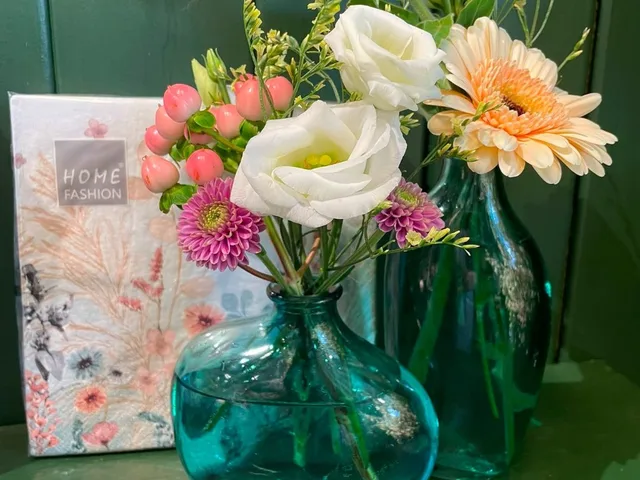 Håndbundet buket med lisianthus og gerbera i en grøn glasvase