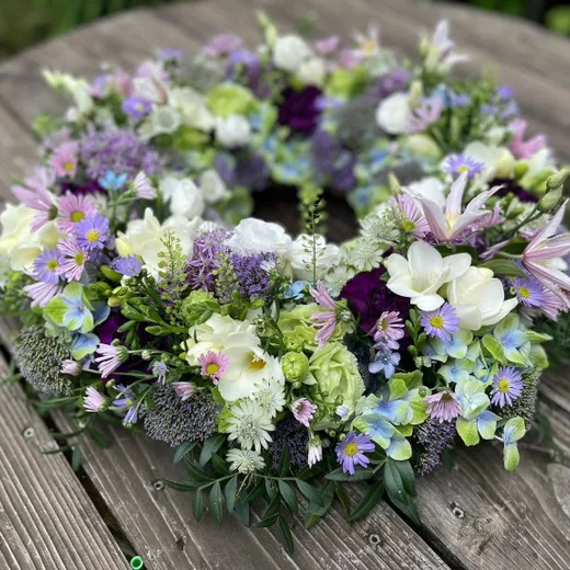 Bårekrans bundet med sæsonens blomster i lyse farver