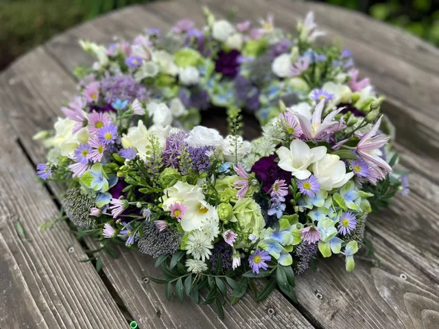 Bårekrans bundet med sæsonens blomster i lyse farver